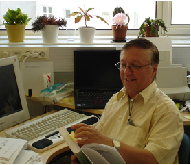 Markku Laitinen selaa kirjaa työpöytänsä ääressä.
